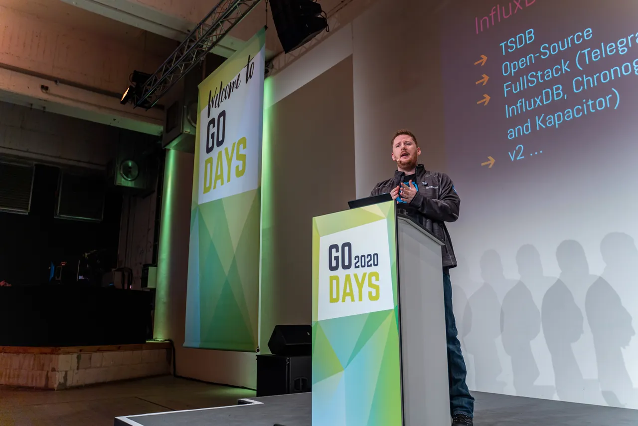 David Flanagan presenting on stage beside a slide about InfluxDB.